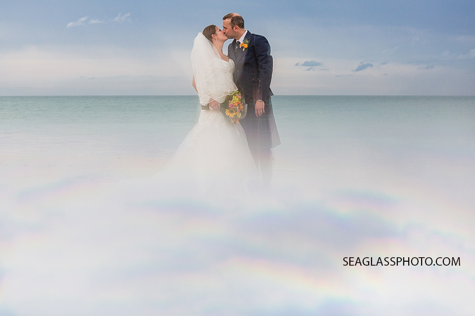 Newly wed couple kisses on the beach with fog surrounding them in Vero Beach Florida