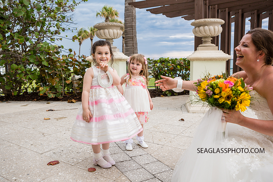 The bride kneels down to say hi to two little girls who are smiling for the camera at the Kimpton Vero Beach hotel and spa in Vero Beach Florida