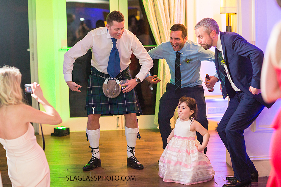 Groomsmen pretend to be monkeys with a little girl at the reception at the Kimpton Vero Beach hotel and spa in Vero Beach Florida
