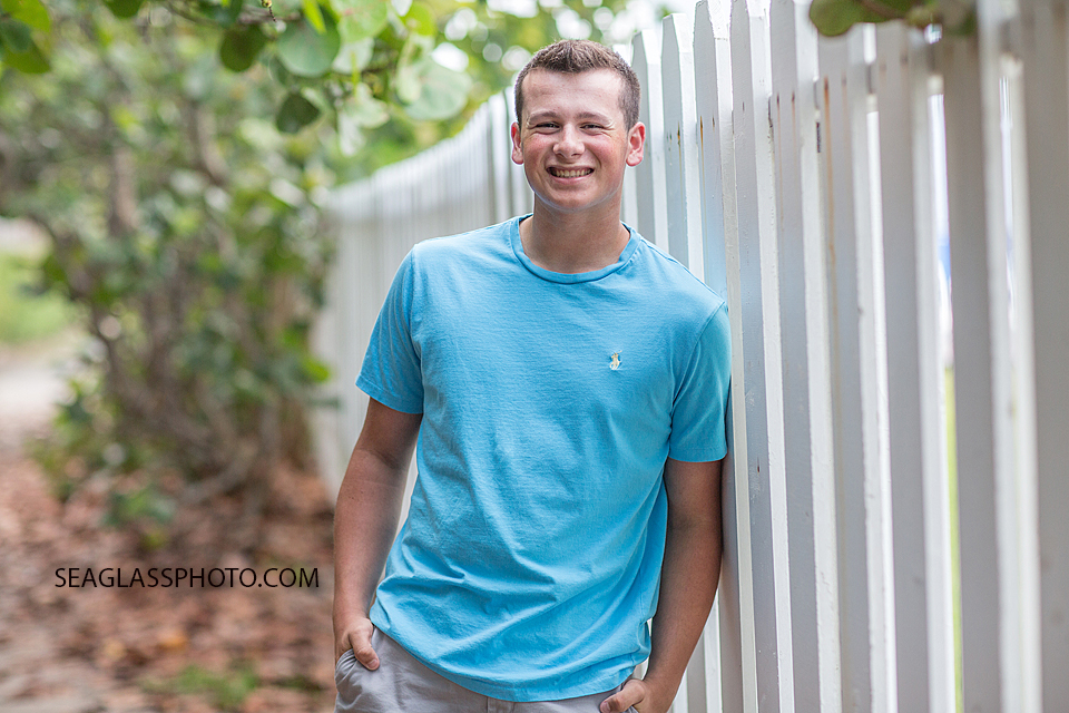 Soon to be senior poses in front of white gate during Senior photo shoot in Vero Beach Florida