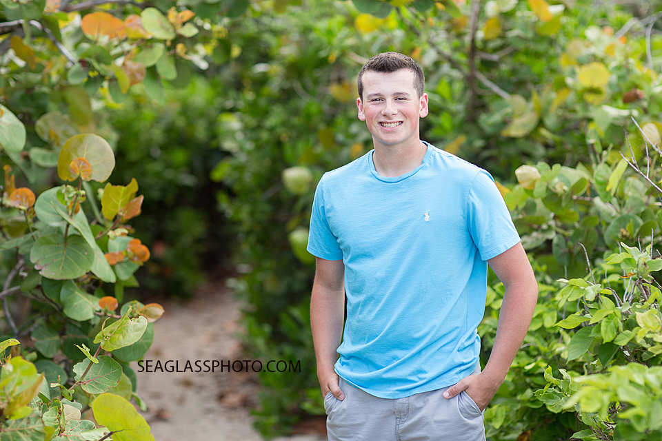 Soon to be senior poses in front of sea grapes on the beach for his senior pictures in Vero Beach Florida