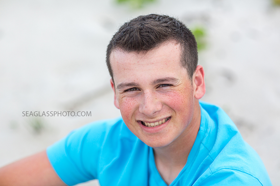 Close up of young man smiling on the beach for his senior pictures in Vero Beach Florida