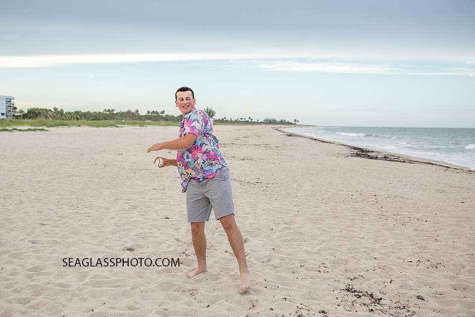 Young man plays baseball on the beach during family/senior photos in Vero Beach Florida