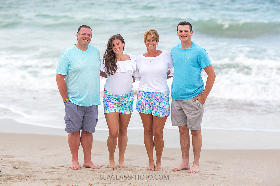 Matching family pose in front of the water on the beach during their family photo shoot in Vero Beach Florida