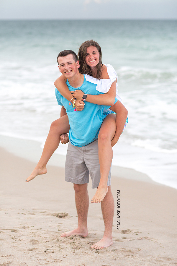 Little brother gives his older sister a piggy back ride on the beach during family photos in Vero Beach Florida