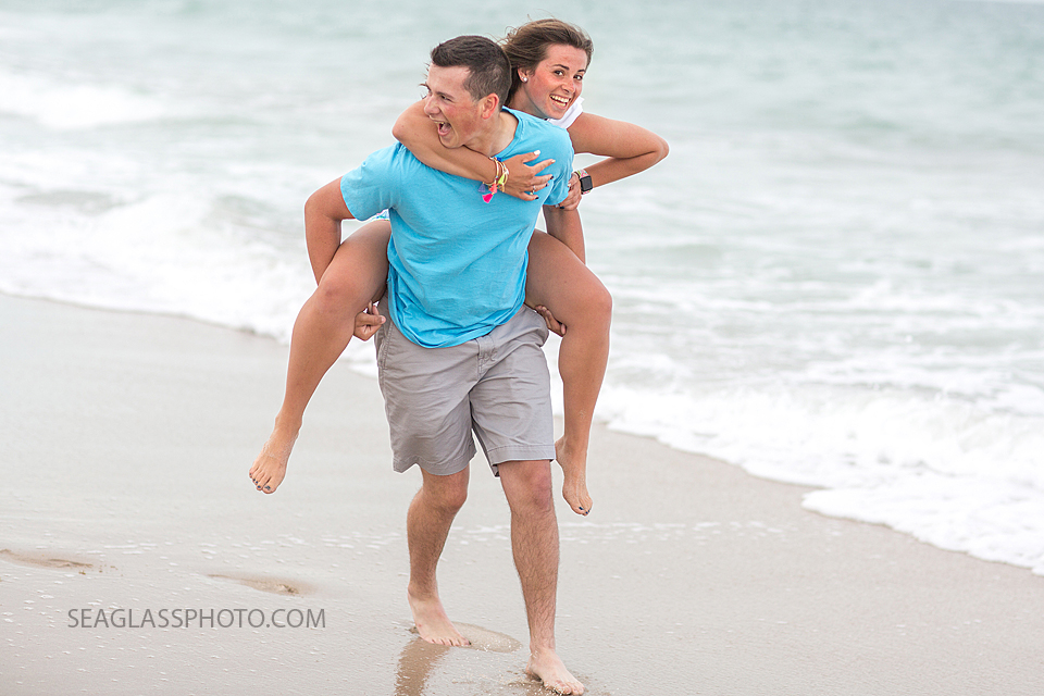 Brother runs while giving his sister a piggy back ride on the beach during family photos in Vero Beach Florida