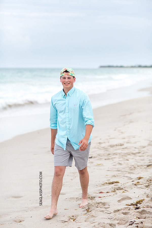 young man walks on the beach during his senior pictures photo shoot in Vero Beach Florida