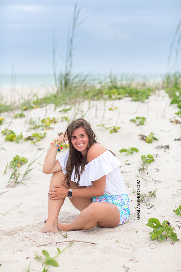 Young lady sits in the duns on the beach during family photo shoot in Vero Beach Florida