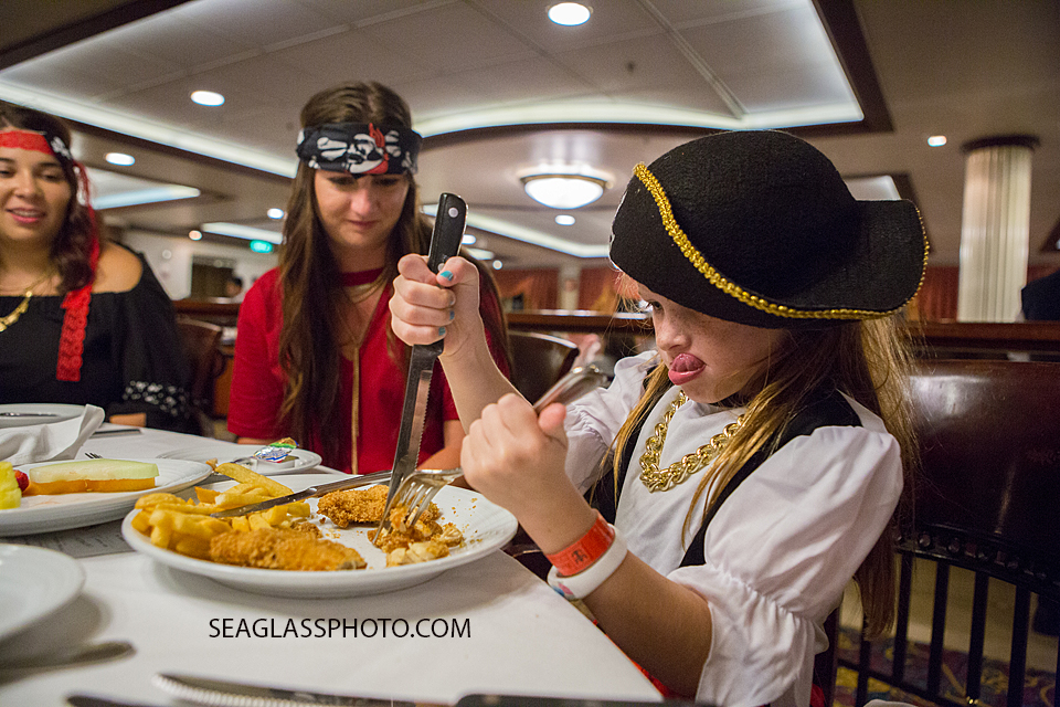 Young pirate digs into her dinner while on a cruise to the bahama's for a twenty first birthday Photographed by a Vero Beach Florida Photographer