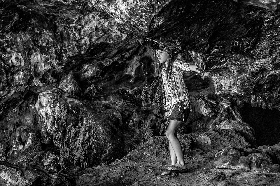 Black and white photo of a young girl climbs a rock in a cave in the bahama's Photographed by a Vero Beach Florida Photographer