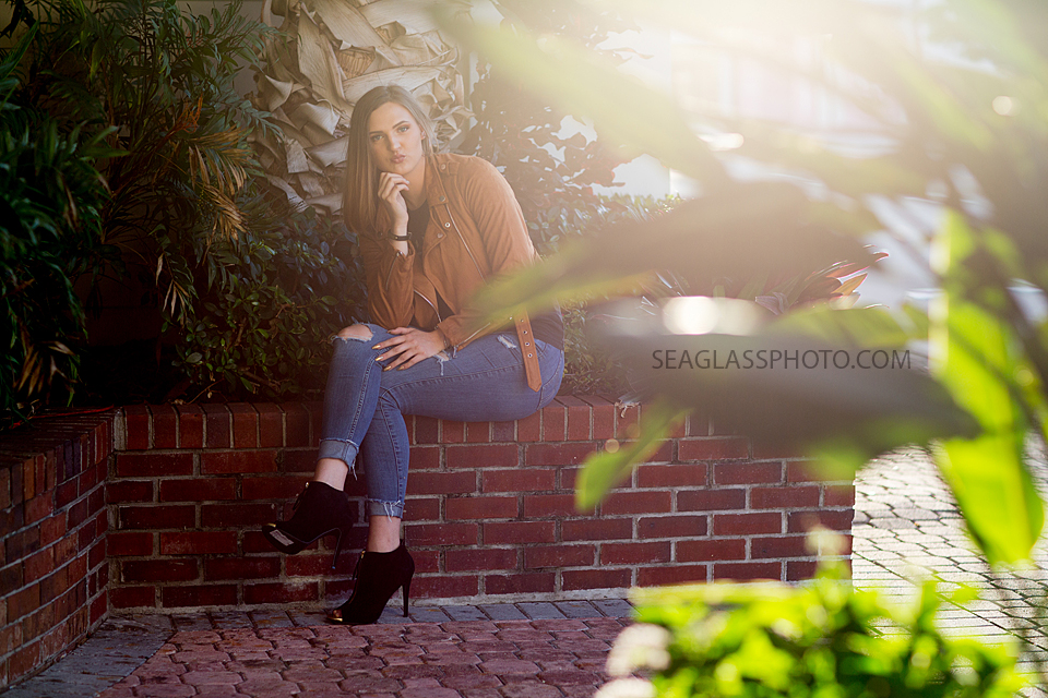 Young lady poses on a brick wall for her senior pictures in Vero Beach Florida