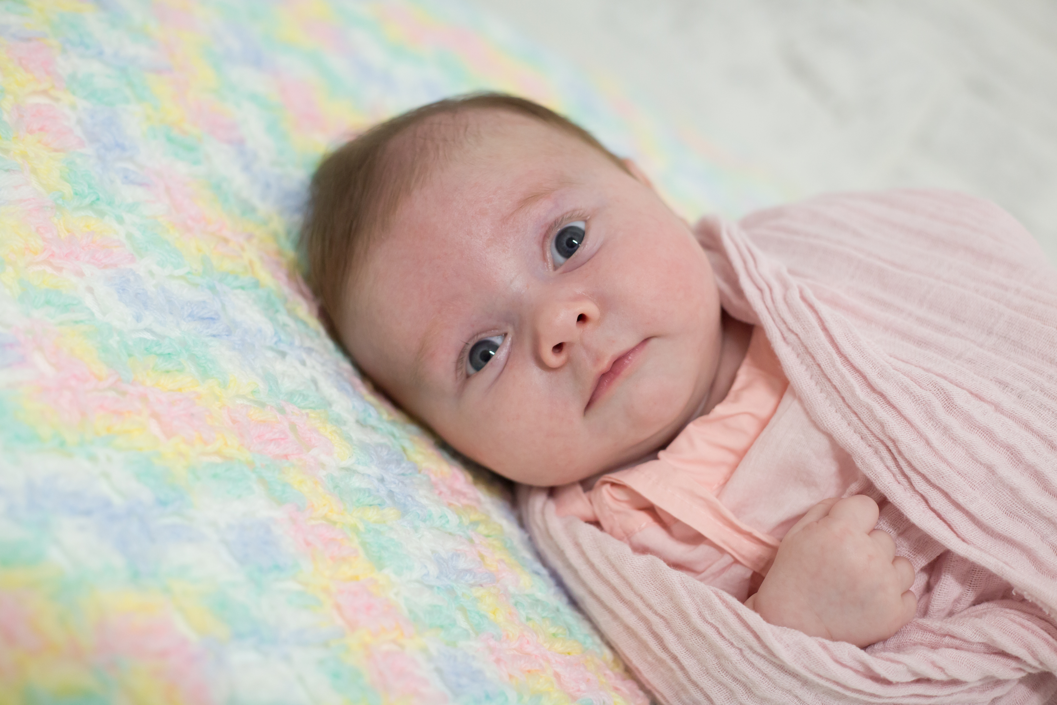 Close up of new born baby girl laying down on rainbow blanket during new born shoot in Vero Beach Florida