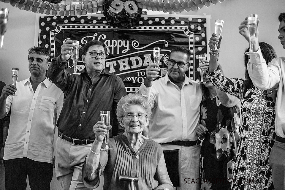 Black and white photo of everyone celebrating a 90th birthday with champagne in Vero Beach Florida
