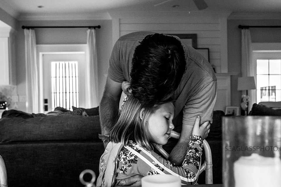 Black and white photo of dad giving his daughter a kiss on the fore head during a home photo shoot in Vero Beach Florida