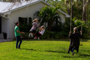 Family swinging in their back yard during a home photo shoot in Vero Beach Florida