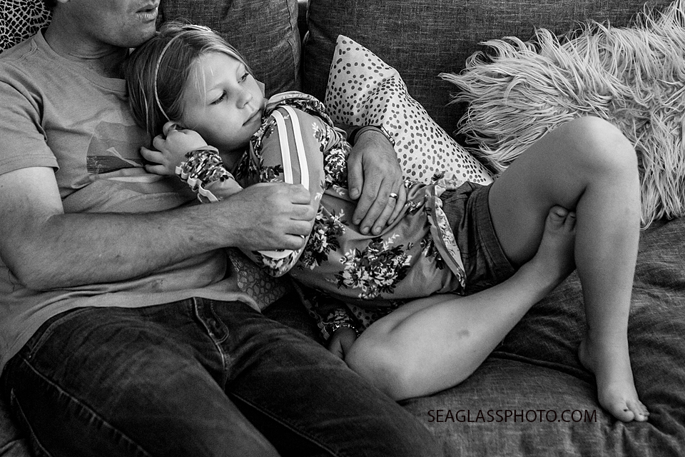 Black and white photo of daughter cuddling up to her dad during a home photo shoot in Vero Beach Florida
