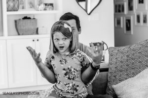 Black and white photo of a young girl pretending her fathers hands are hers during a home photo shoot in Vero Beach Florida