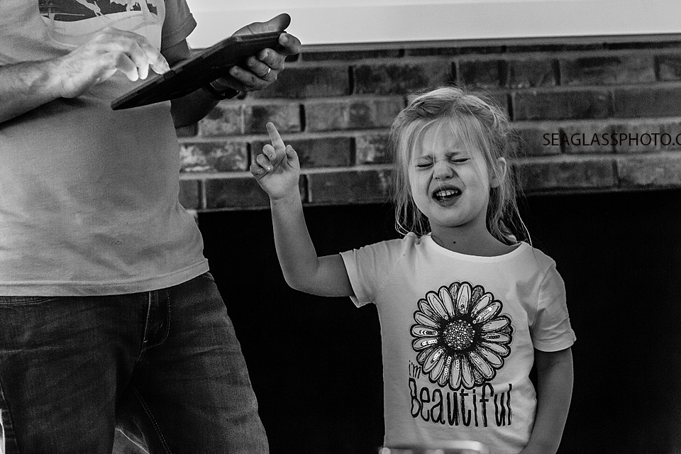 Black and white photo of a young girl pointing at her father during a home photo shoot in Vero Beach Florida