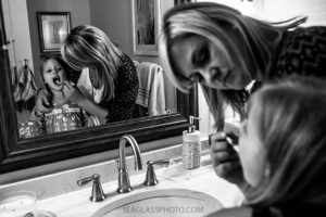 Black and white photo of mom helping her daughter brush her teeth before bed time during a home photo shoot in Vero Beach Florida