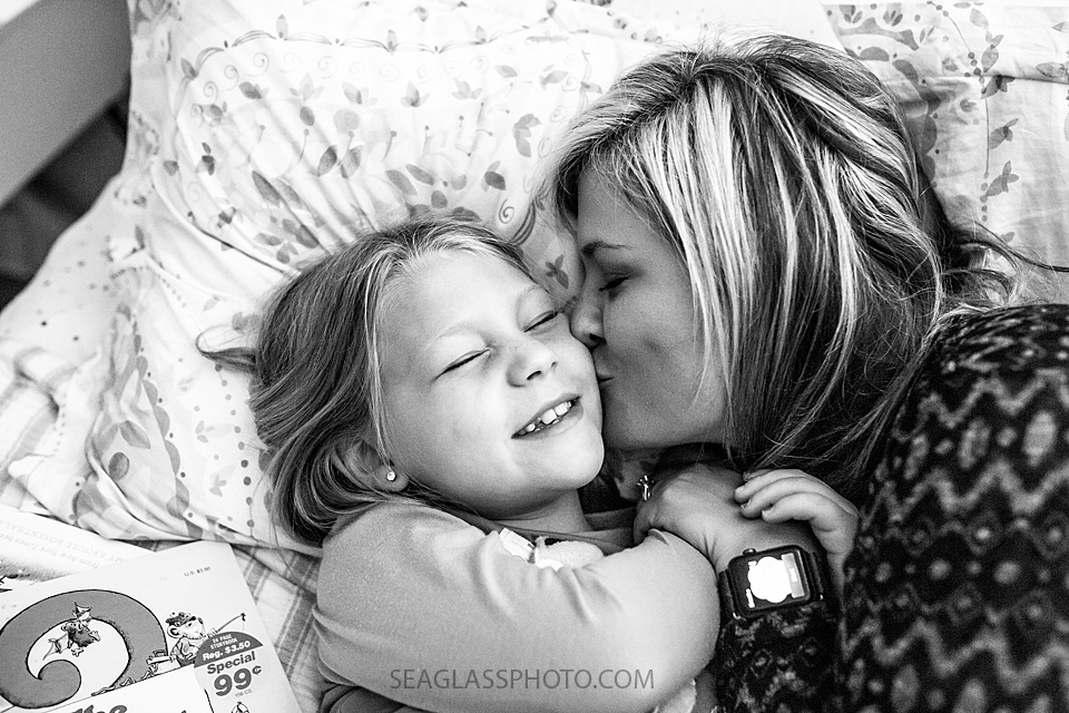 Close up black and white photo of mom kissing her daughter on the cheek during a home photo shoot in Vero Beach Florida