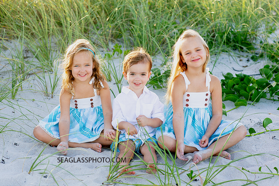 Three Siblings playing in the sand together on the beach during family photos in Vero Beach Florida