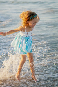 Little girl jumping in the water on the beach during family photos in Vero Beach Florida