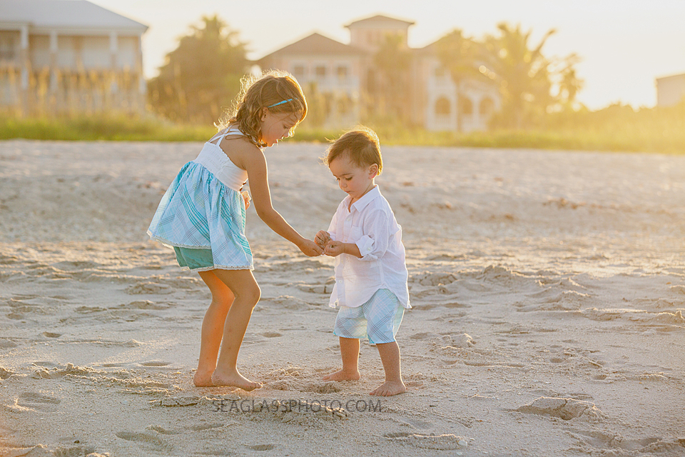 Big sister helping her little brother find shells on the beach during family photos in Vero Beach Florida