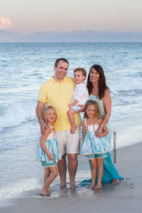 Family of five smile on the beach during family photos in Vero Beach Florida