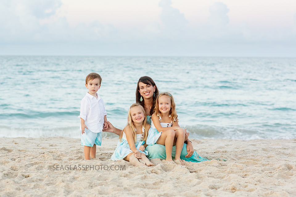 Mom sits with her three kids on the beach during family photos in Vero Beach Florida