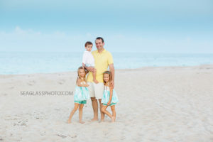 Father stands with his three kids on the beach during family photos in Vero Beach Florida