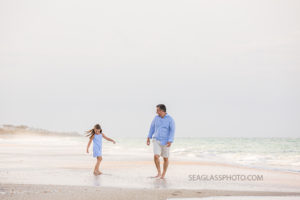 Father and daughter walk along the beach during a family photo shoot in Vero Beach Florida