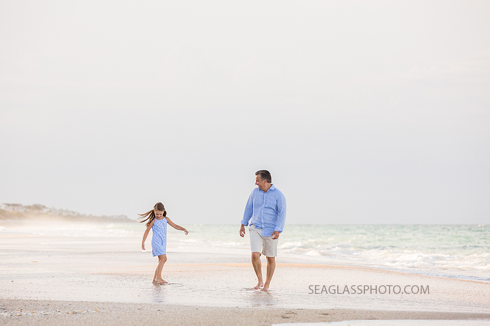 Father and daughter walk along the beach during a family photo shoot in Vero Beach Florida