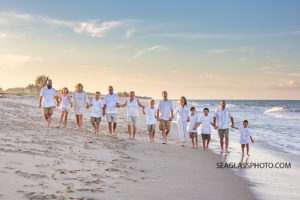 Family holds hands and takes a walk on the beach during family photo shoot in Vero Beach Florida