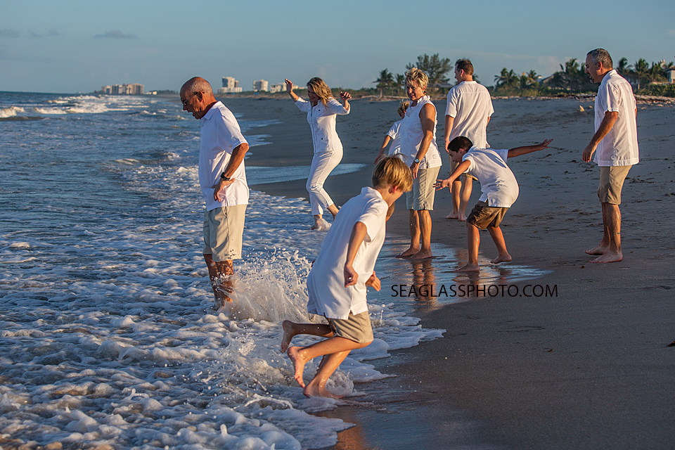 Family jumps for joy in the wake of the ocean during family photo shoot in Vero Beach Florida