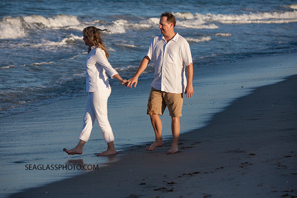 Husband and wife take a break from the kids and take a walk on the beach during family photo shoot in Vero Beach Florida