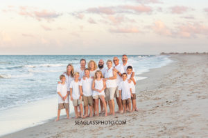 Family squeeze together for a family photo by the ocean during family photo shoot in Vero Beach Florida