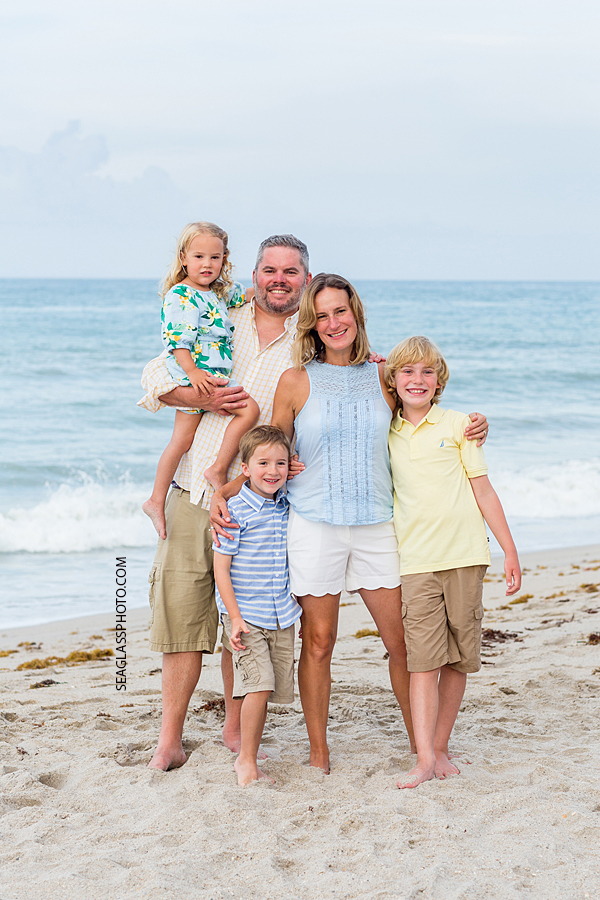 Family of five hug for a pic in front of the ocean during family photo shoot in Vero Beach Florida