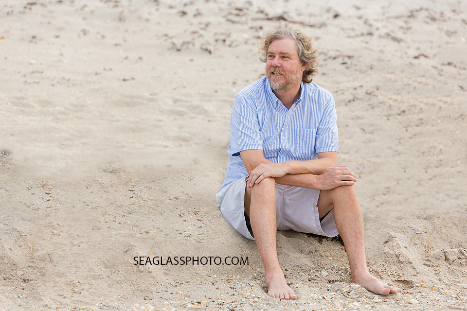 Father sits in the sand during family photo shoot in Vero Beach Florida