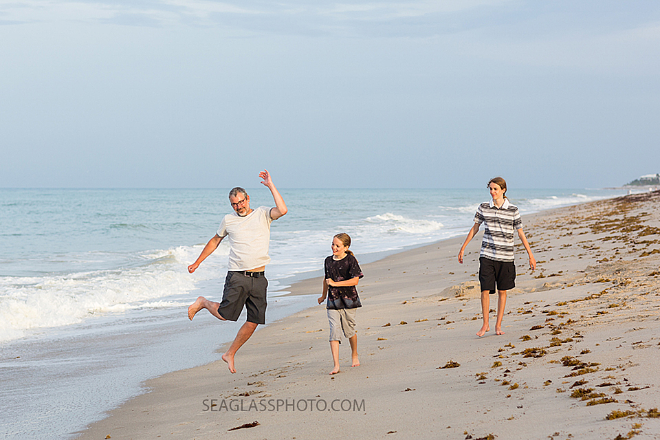 Father runs on the beach with his two sons during family photo shoot in Vero Beach Florida
