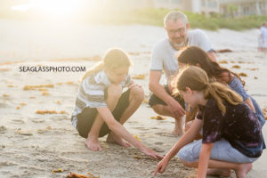 Family dig in the sand on the beach during family photo shoot in Vero Beach Florida