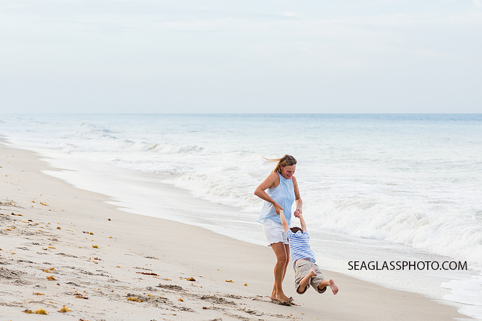 Mom swings her son on the beach during family photo shoot in Vero Beach Florida