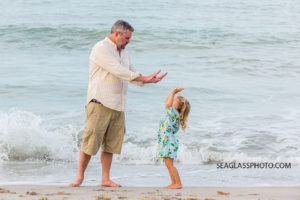 Father high fives his daughter by the ocean during family photo shoot in Vero Beach Florida