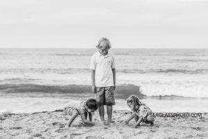 Black and white photo of three siblings playing in the sand on the beach during family photo shoot in Vero Beach Florida