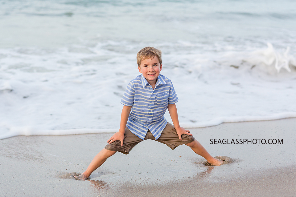 Little boy getting his feet stuck in the sand during family photo shoot in Vero Beach Florida
