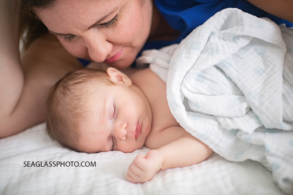Mother lies next to her newborn son during newborn session in Downtown Vero Beach Florida