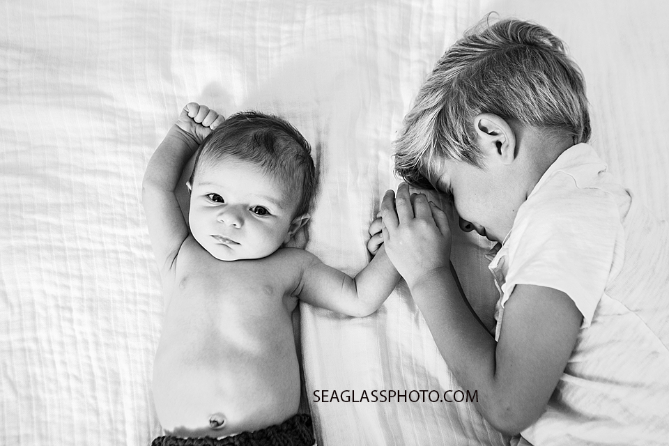 Black and white photo of newborn baby boy next to his big brother during newborn session in Downtown Vero Beach Florida