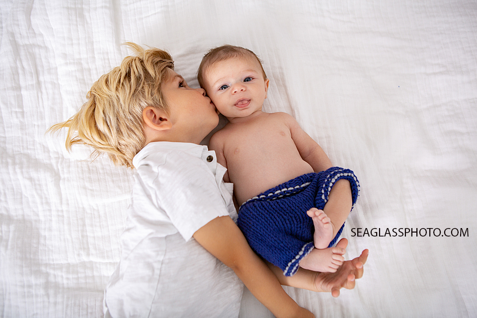 Big brother kisses little brother during newborn session in Downtown Vero Beach Florida