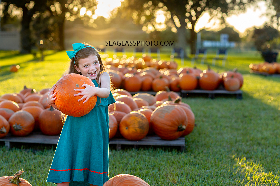 Little girl Picking her favorite pumpkin up taken by a Vero Beach Florida Photographer