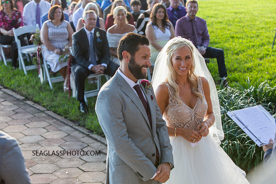 Bride and Groom smiling while the officiant speaks photographed by a Vero Beach Photographer