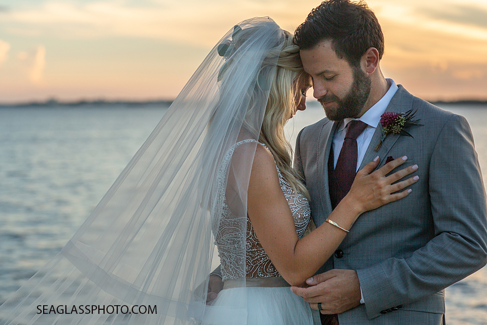 Close up of husband and wife holding each other in front of the bay photographer by a Vero Beach Photographer